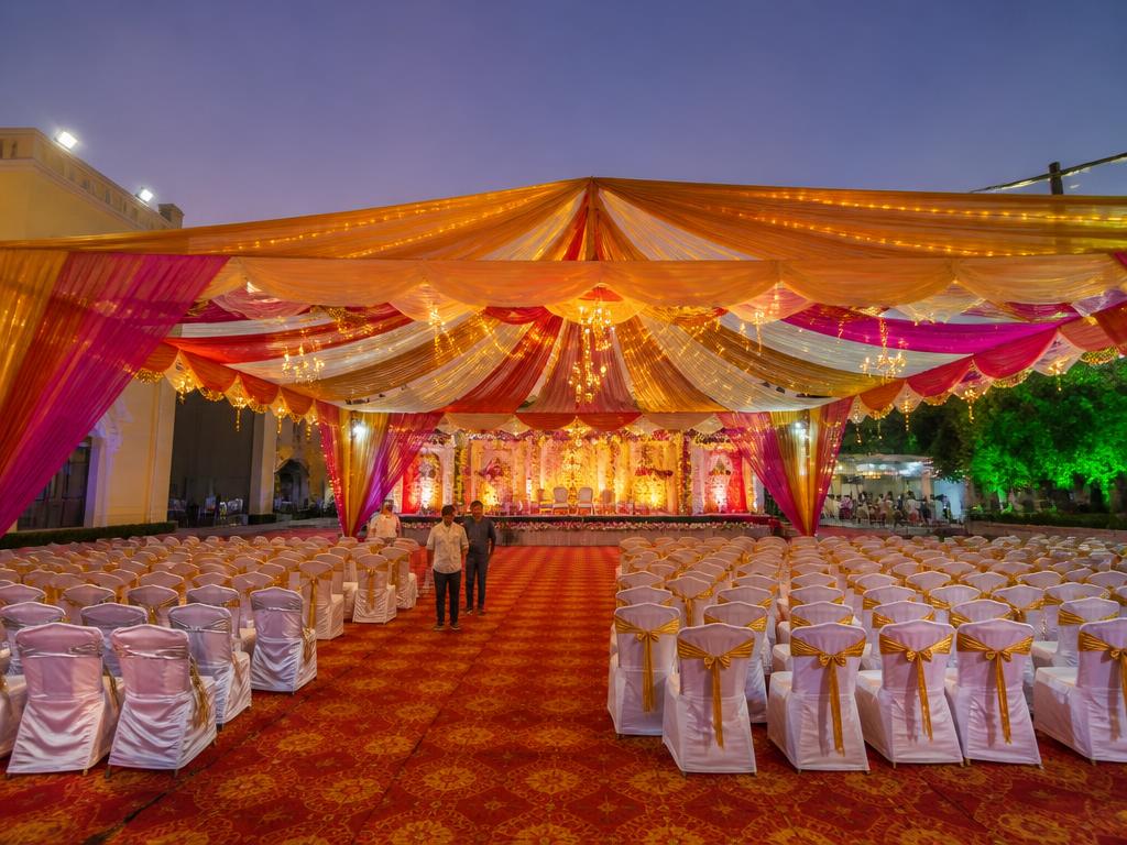 Brightly lit shamiana tent event setup at dusk